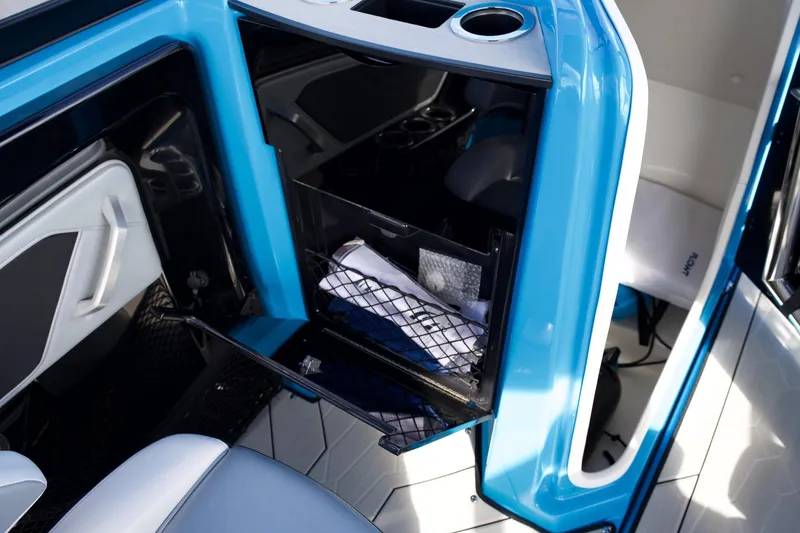 Slide: The Image of 2023 Yamaha Boats 255XD interior storage compartment with blue accents and cup holder. - 20