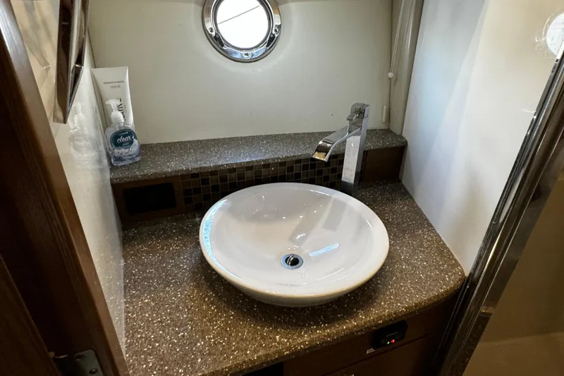 Slide: The Image of Bathroom sink area in 2014 Cruisers Yachts 45 Cantius, featuring modern fixtures and porthole window. - 20