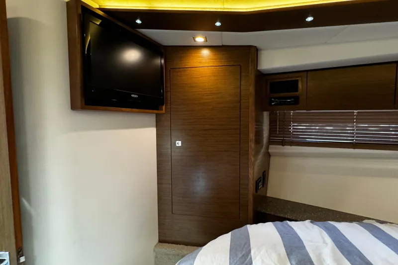 Slide: The Image of Interior of 2014 Cruisers Yachts 45 Cantius with TV, wood paneling, and striped bedding. - 22