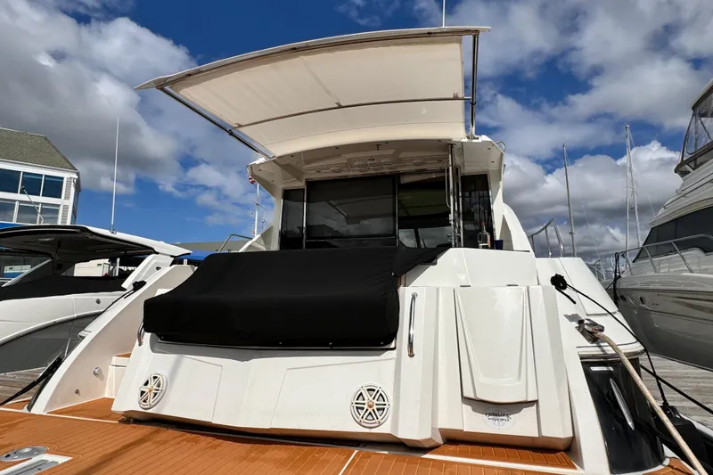 Slide: The Image of 2014 Cruisers Yachts 45 Cantius docked, showcasing sleek design and spacious deck under a cloudy sky. - 4