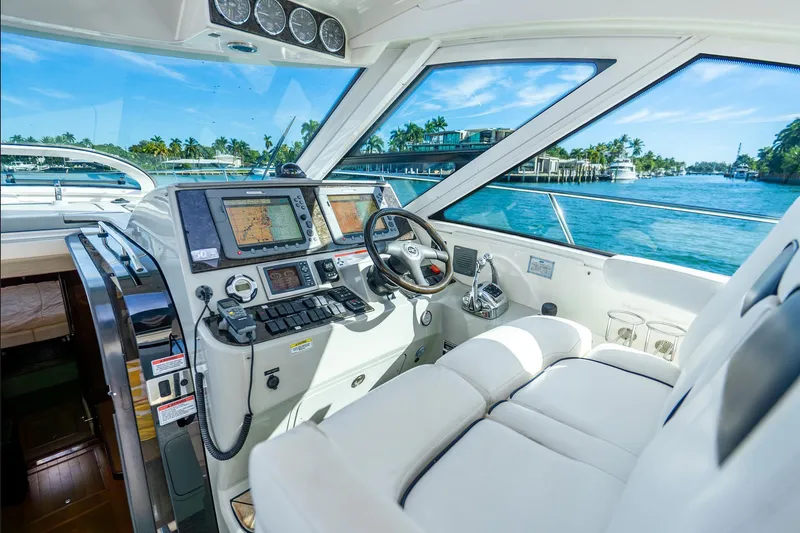 Slide: The Image of 2009 Sea Ray 470 Sundancer helm with navigation screens, steering wheel, and waterfront view. - 11