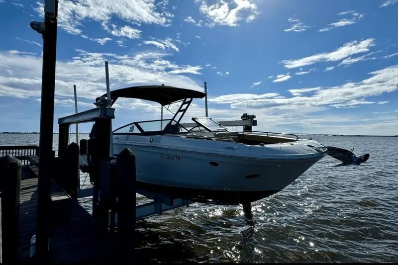 Slide: The Image of 2024 Sea Ray SDX 270 boat docked, covered, with a sunny waterfront view. - 1