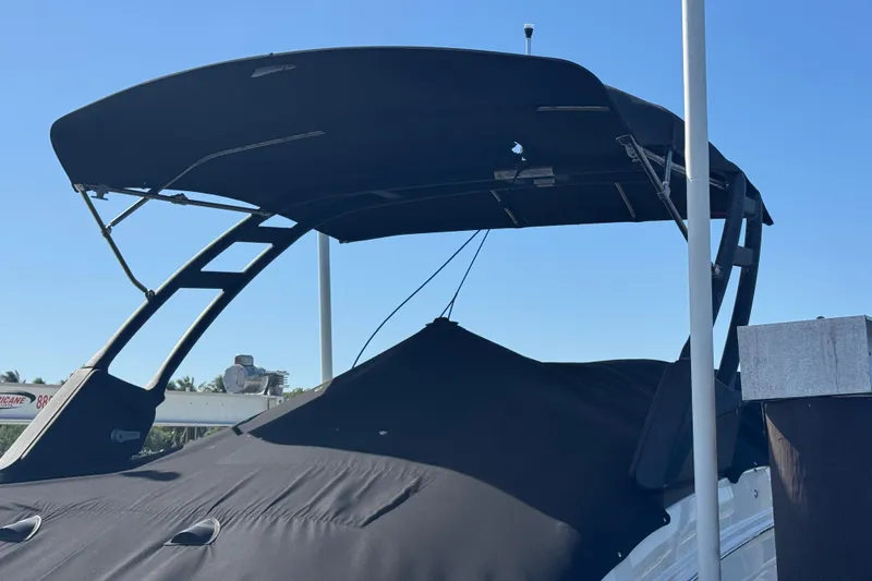 Slide: The Image of 2024 Sea Ray SDX 270 boat with black canopy and cover, docked under clear blue sky. - 36