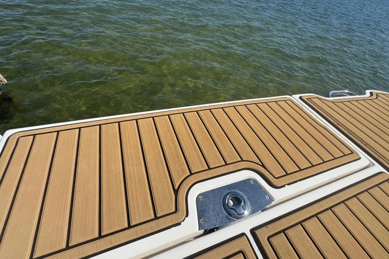 Slide: The Image of 2024 Sea Ray SDX 270 swim platform with teak-style decking on calm water. - 50