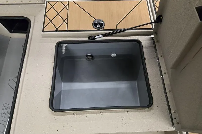 Slide: The Image of Open storage compartment on 2026 Avid 18 Vertex boat with wood-patterned lid. - 21