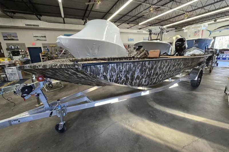 The Image of 2026 Avid 20 Rogue SC boat with camouflage design on a trailer in a showroom. - 0