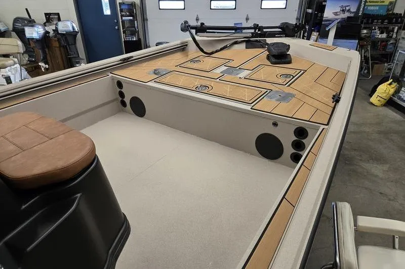 Slide: The Image of 2026 Avid 22 Rogue CC boat interior with wood accents and seating in a showroom. - 6