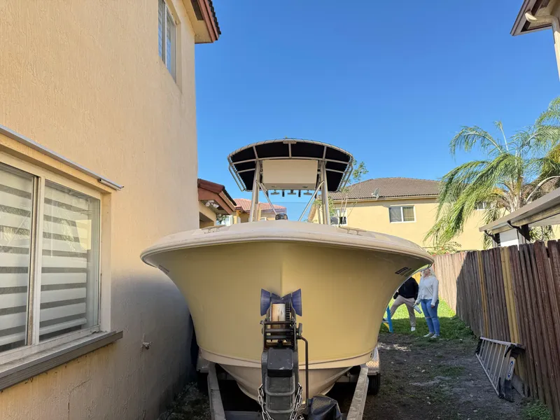 Slide: The Image of 2005 Sea Hunt Triton 232 boat parked between houses under clear blue sky. - 12