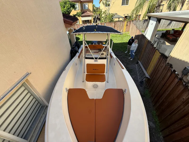 Slide: The Image of 2005 Sea Hunt Triton 232 boat with brown seating, parked in a narrow backyard. - 15