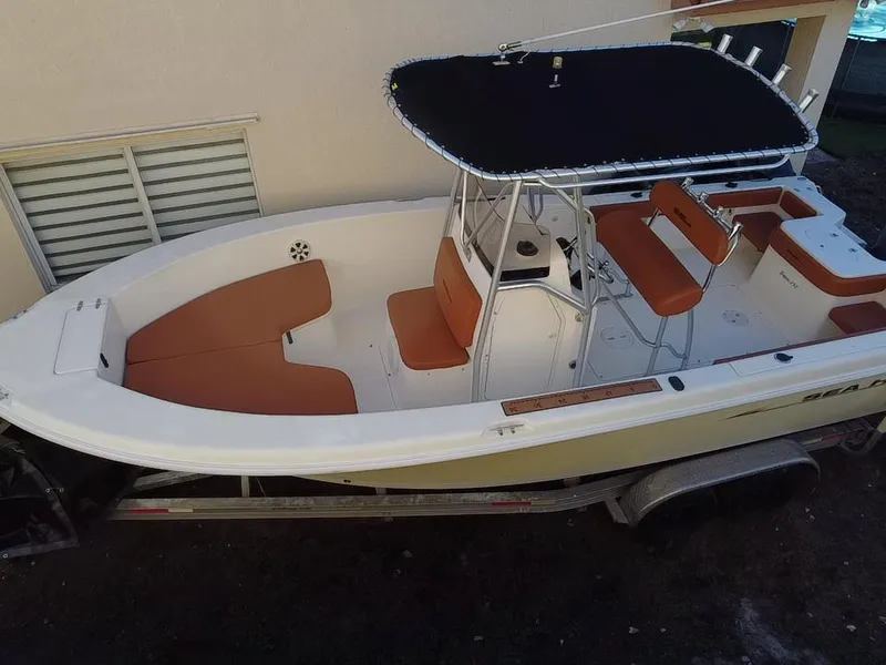 Slide: The Image of 2005 Sea Hunt Triton 232 boat with tan seating and black canopy on trailer. - 2