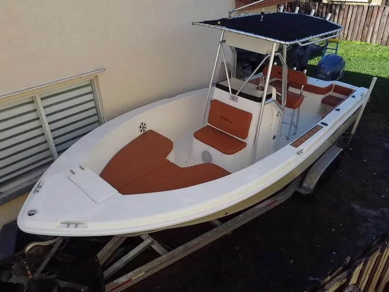 Slide: The Image of 2005 Sea Hunt Triton 232 boat on trailer, featuring brown seating and a black canopy. - 4