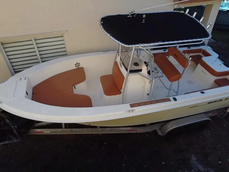 Slide: The Image of 2005 Sea Hunt Triton 232 boat with tan seating and black canopy on trailer. - 5