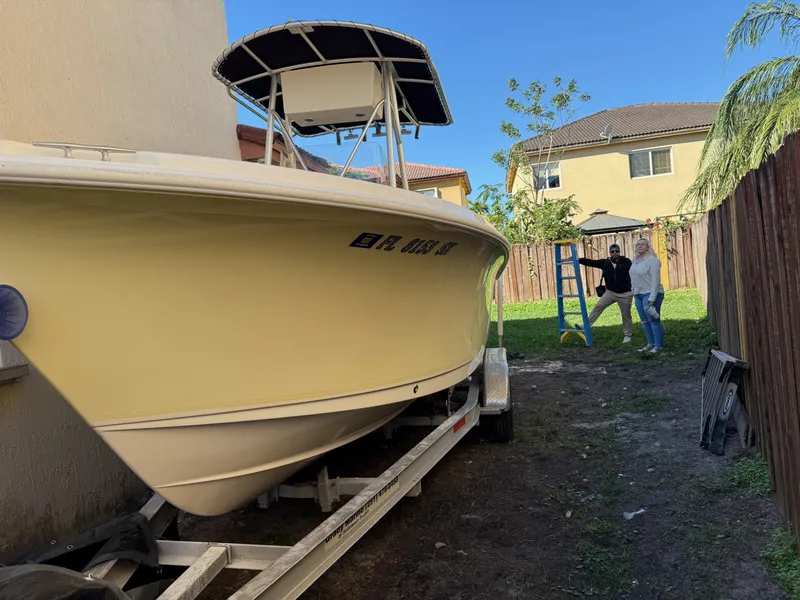 Slide: The Image of 2005 Sea Hunt Triton 232 boat on trailer beside house, with two people nearby. - 9