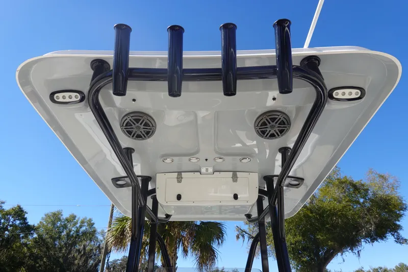 Slide: The Image of 2026 Sea Hunt Ultra 219 boat T-top with rod holders and speakers, under clear blue sky. - 18