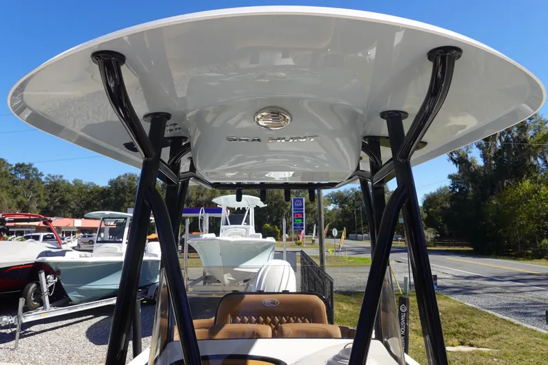 Slide: The Image of 2026 Sea Hunt Ultra 219 boat with T-top, displayed outdoors on a sunny day. - 27