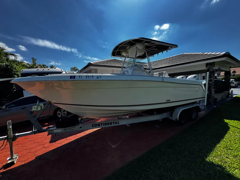 The Image of 2004 Robalo R 260 boat on trailer, parked in driveway under clear blue sky. - 0