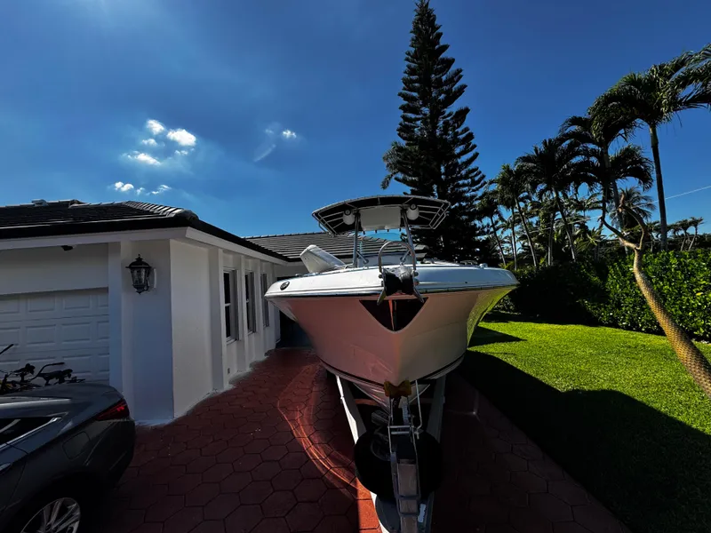 Slide: The Image of 2004 Robalo R 260 boat parked in a driveway beside a house. - 2