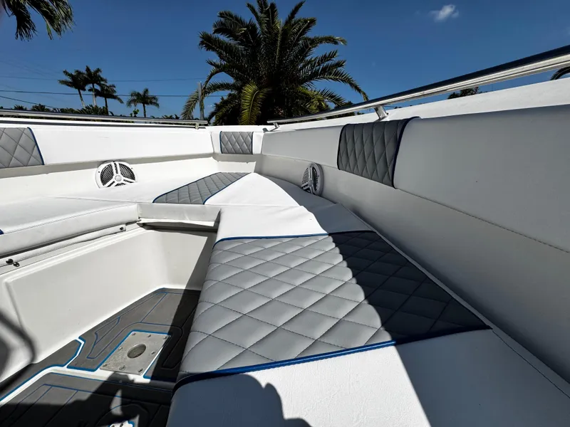 Slide: The Image of 2004 Robalo R 260 boat interior with cushioned seating and palm trees in the background. - 23