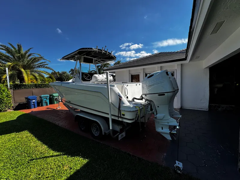 Slide: The Image of 2004 Robalo R 260 boat on trailer beside house, under clear blue sky. - 4