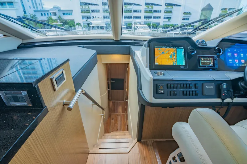 Slide: The Image of 2018 Sea Ray L590 yacht interior helm station with navigation screens and stairs. - 36