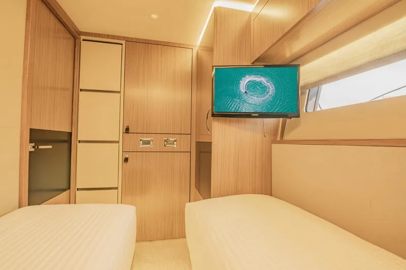 Slide: The Image of 2018 Sea Ray L590 yacht cabin with twin beds and wall-mounted TV. - 49