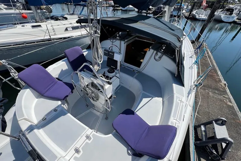 Slide: The Image of 1995 Hunter 336 sailboat cockpit with purple cushions, docked in a marina. - 7