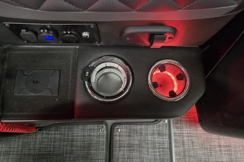 Slide: The Image of 2026 AquaPatio 235 DFL interior console with cup holders and controls, illuminated in red. - 12