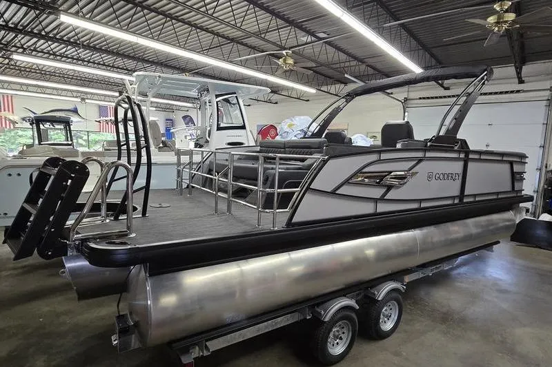 Slide: The Image of 2026 AquaPatio 235 DFL pontoon boat in showroom, featuring sleek design and modern amenities. - 2