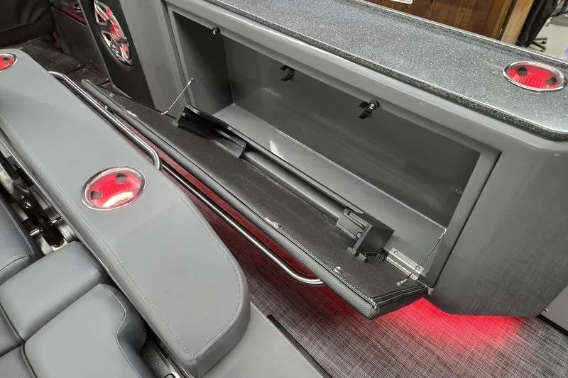 Slide: The Image of 2026 AquaPatio 235 DFL boat interior with open storage compartment and cup holders. - 7