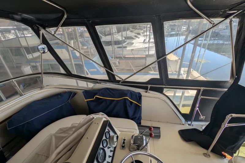 Slide: The Image of 1984 Chris-Craft 382 Commander cockpit with marina view, featuring helm controls and seating. - 13