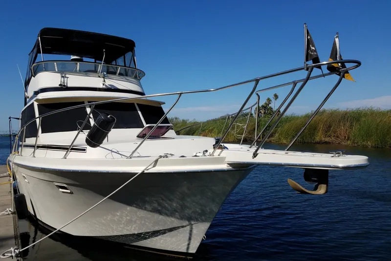 Slide: The Image of 1984 Chris-Craft 382 Commander yacht docked on a sunny day, featuring sleek design and flags. - 2