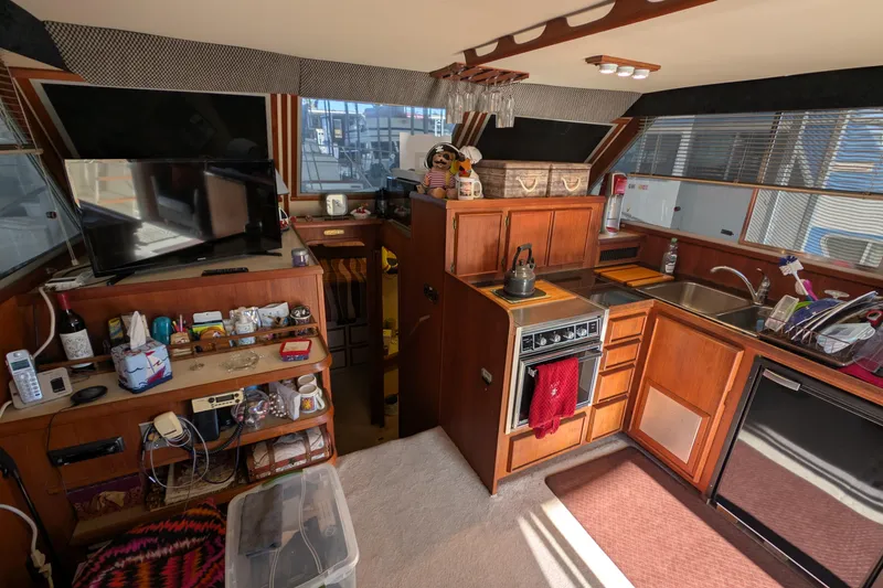 Slide: The Image of 1984 Chris-Craft 382 Commander interior with kitchen, TV, and wooden cabinetry. - 33