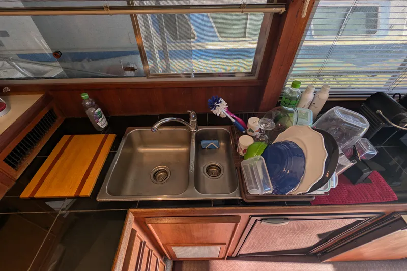 Slide: The Image of 1984 Chris-Craft 382 Commander kitchen sink with dishes and cleaning supplies. - 44