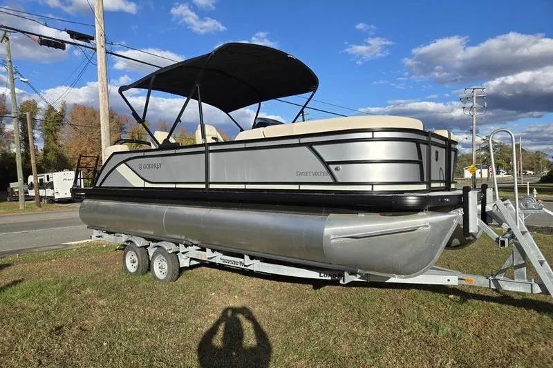 Slide: The Image of 2025 Godfrey Sweetwater 2286 QS pontoon boat on trailer, under clear blue sky. - 3