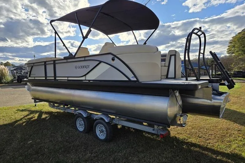 Slide: The Image of 2025 Godfrey Sweetwater 2286 QS pontoon boat on trailer, under a cloudy sky. - 9