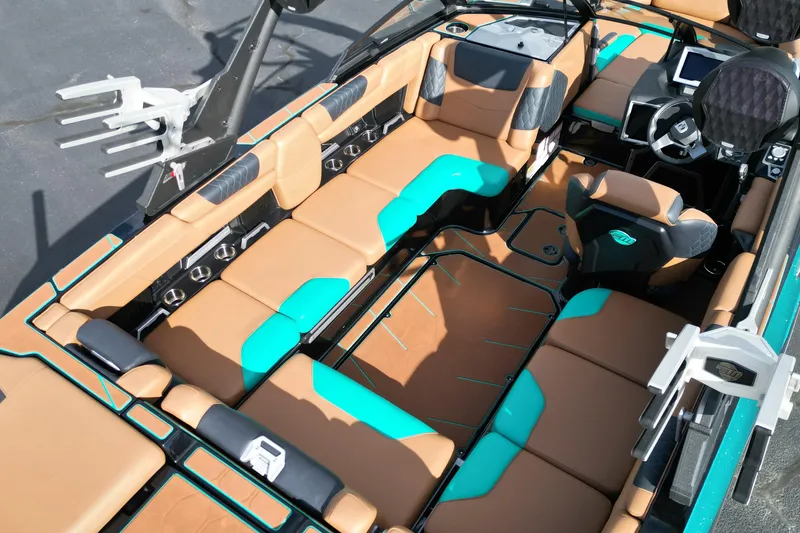 Slide: The Image of 2023 Malibu M220 boat interior with tan and teal seating, modern dashboard, and cup holders. - 13