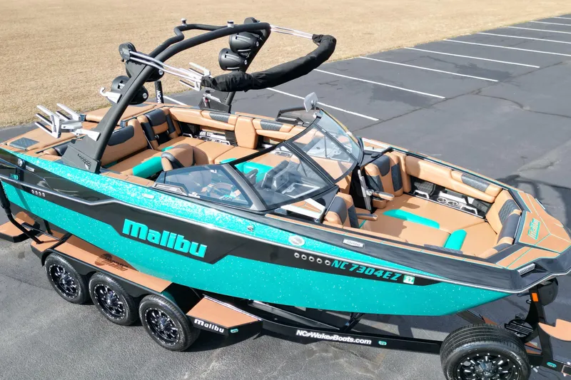 Slide: The Image of 2023 Malibu M220 boat with vibrant teal and tan interior, parked on a trailer. - 4