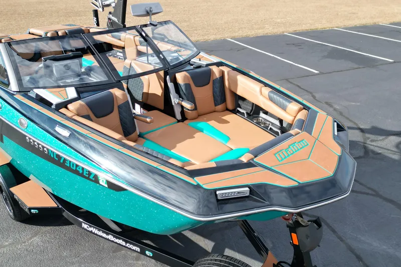 Slide: The Image of 2023 Malibu M220 boat with stylish interior and teal accents parked on asphalt. - 5