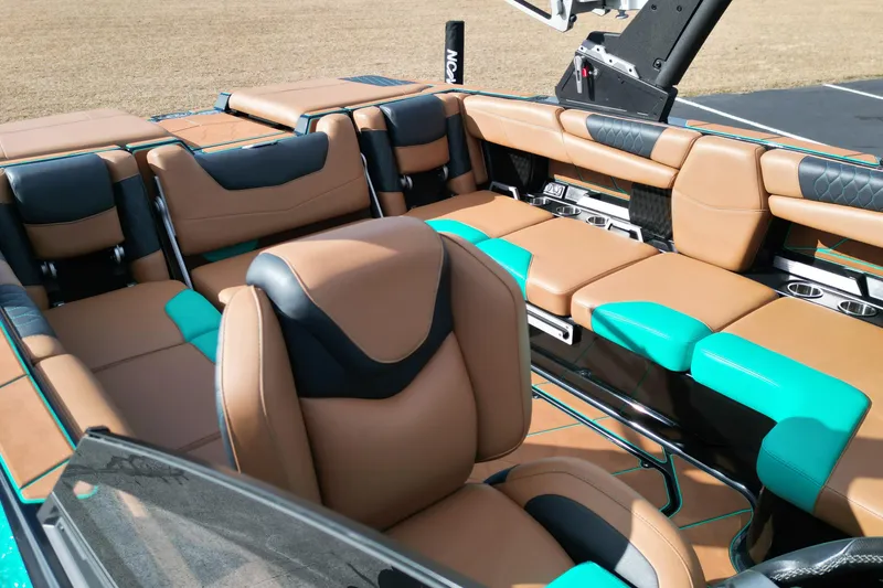 Slide: The Image of 2023 Malibu M220 boat interior with tan and teal seating, featuring cup holders and sleek design. - 6