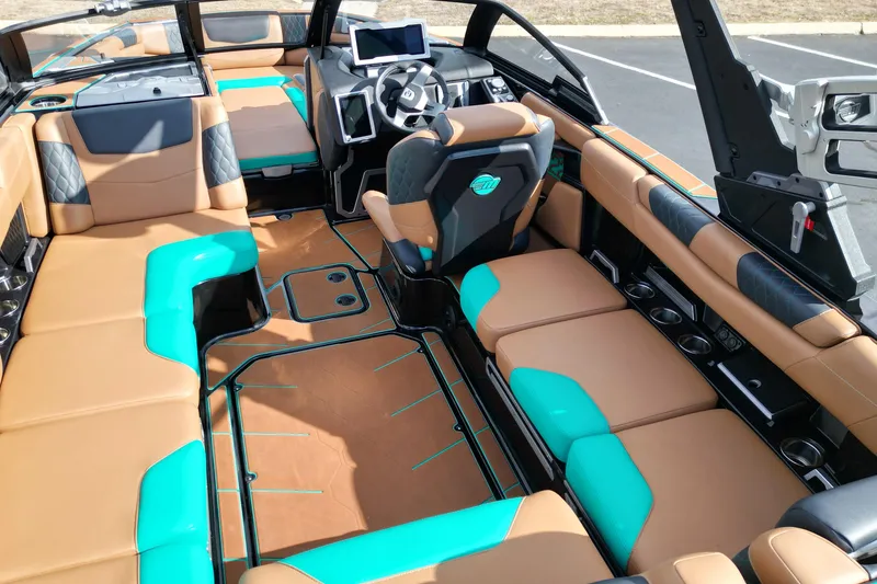 Slide: The Image of 2023 Malibu M220 boat interior with tan and teal seating, modern dashboard, and spacious layout. - 9
