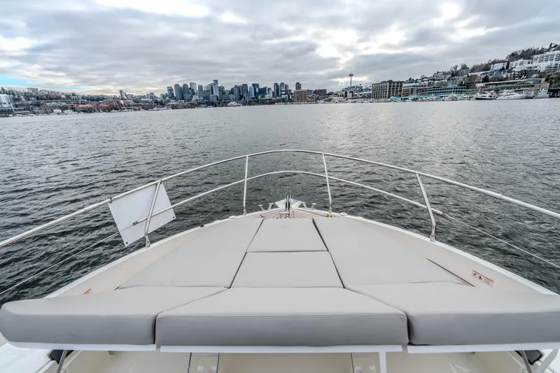 Slide: The Image of Bow view of 2026 Absolute 48 Coupe yacht approaching city skyline under cloudy skies. - 10