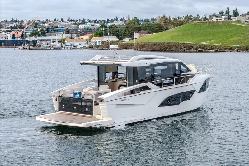 Slide: The Image of 2026 Absolute 48 Coupe yacht cruising on a scenic waterfront. - 3