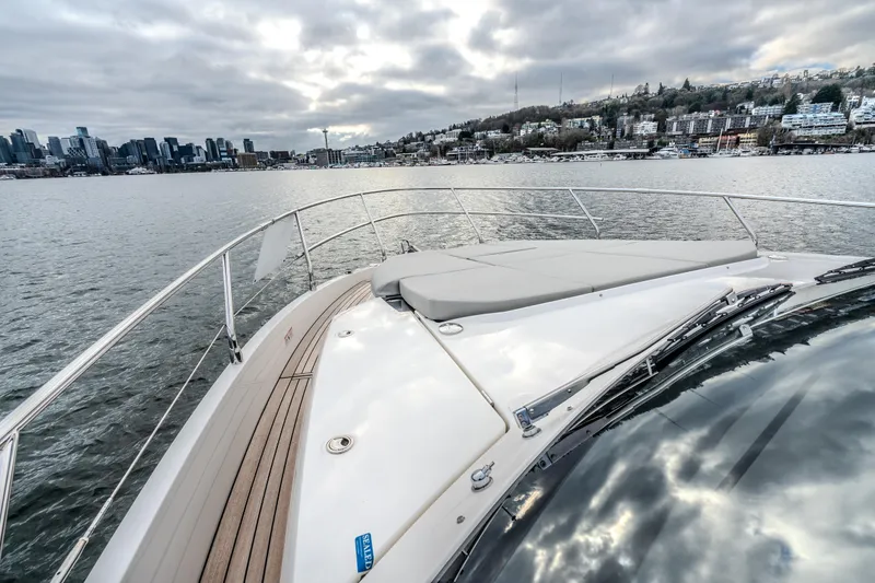Slide: The Image of 2026 Absolute 48 Coupe yacht cruising near city skyline under cloudy skies. - 9