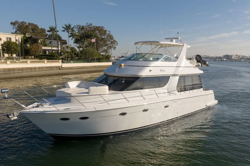 The Image of 1999 Carver 53 Voyager yacht cruising near a waterfront property. - 0