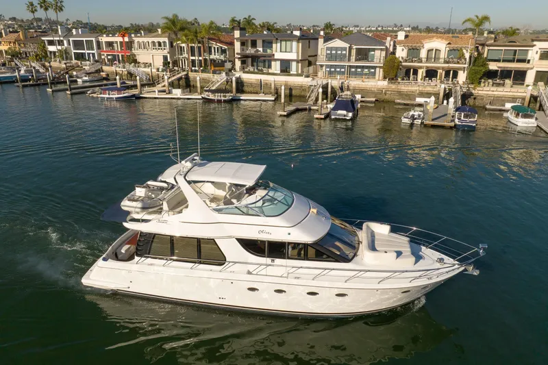 Slide: The Image of 1999 Carver 53 Voyager yacht cruising near waterfront homes. - 2