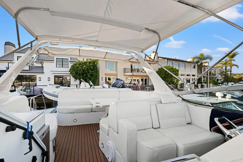 Slide: The Image of 1999 Carver 53 Voyager yacht interior with white seating, docked near waterfront homes. - 33