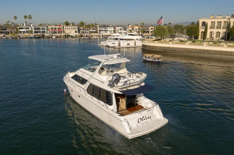 Slide: The Image of 1999 Carver 53 Voyager yacht cruising in a scenic waterfront area with luxury homes. - 38