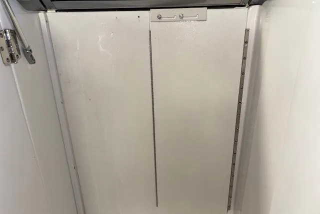 Slide: The Image of 2015 Hurricane SunDeck 2200 OB interior compartment with white panel and metal hinges. - 40