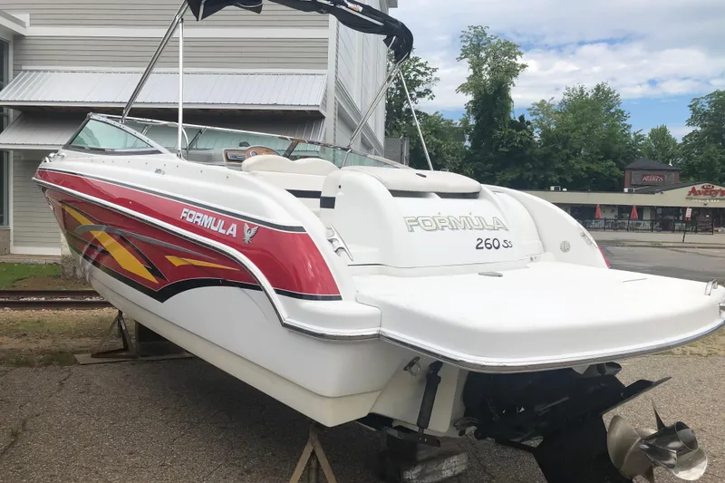 Slide: The Image of 2007 Formula 260 Sun Sport boat with vibrant red and yellow graphics, parked outdoors. - 5