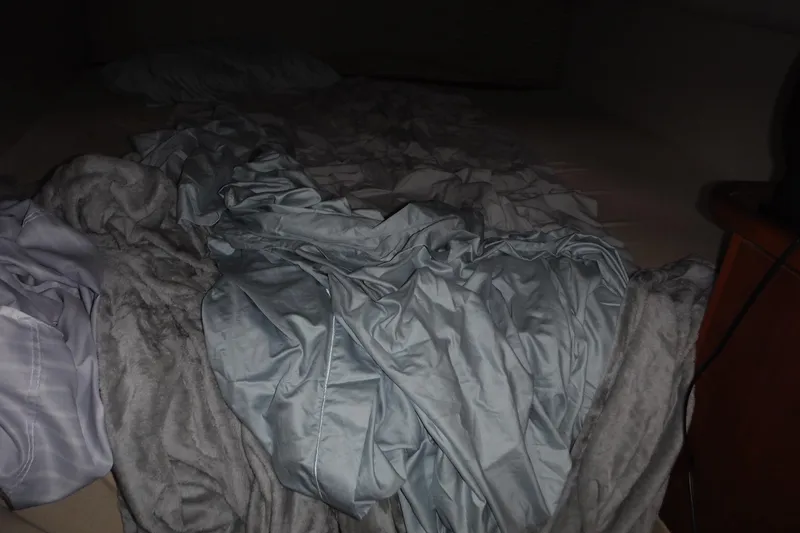 Slide: The Image of Messy bed with crumpled sheets inside a 1999 Cruisers 4270 Express boat cabin. - 19